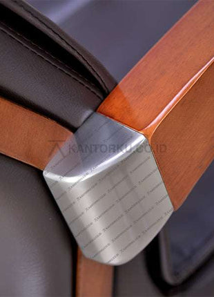 Close-up of a wooden chair armrest with a metal bracket, featuring the brand 'Kantorku. Temukan Kursi Kerja Pimpinan kamu hanya Di kantorku.co.id Solusi Tepat Kebutuhan Kantor Kamu!!